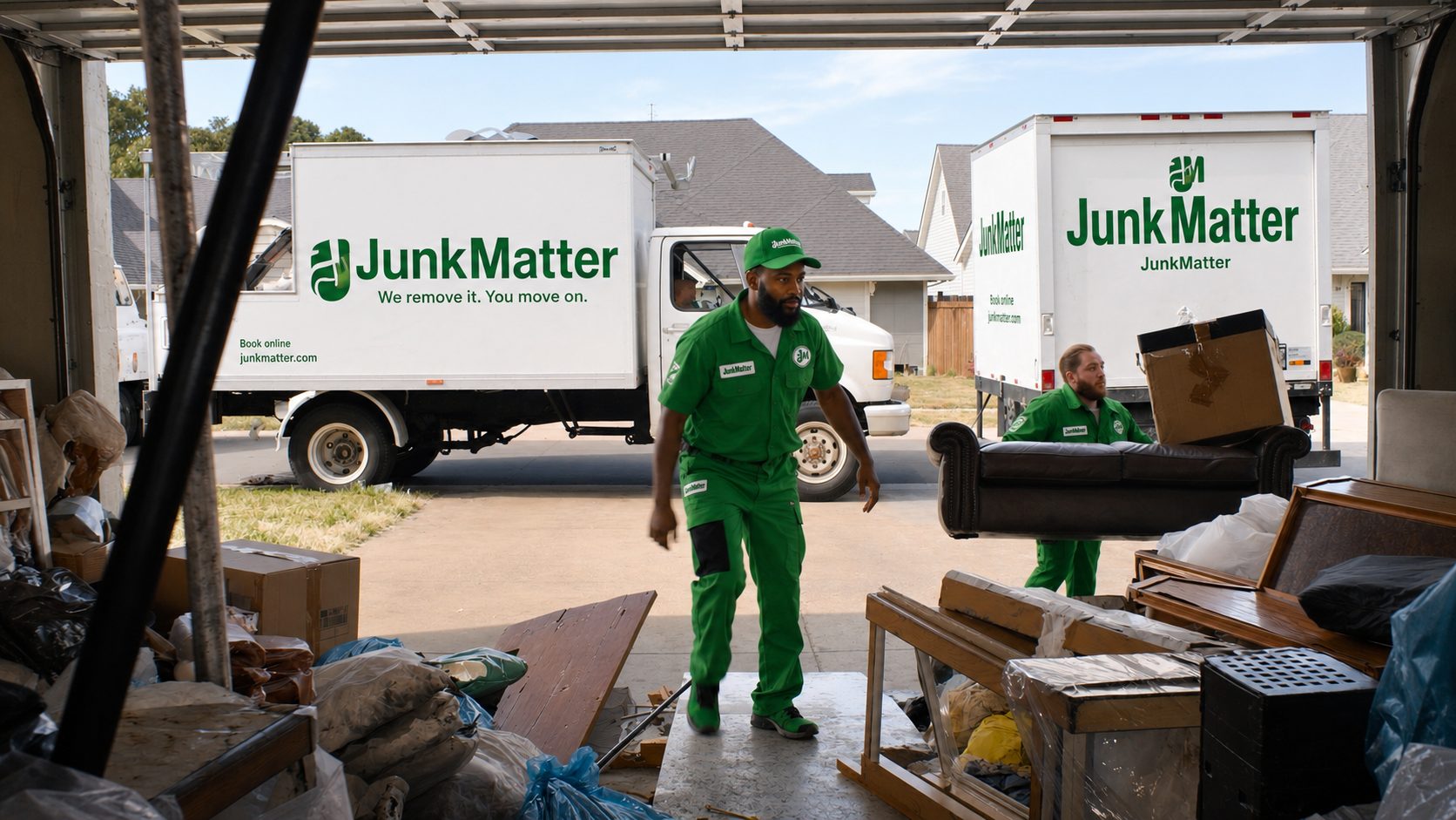 JunkMatter crew clearing a full garage, with two branded trucks parked on the driveway