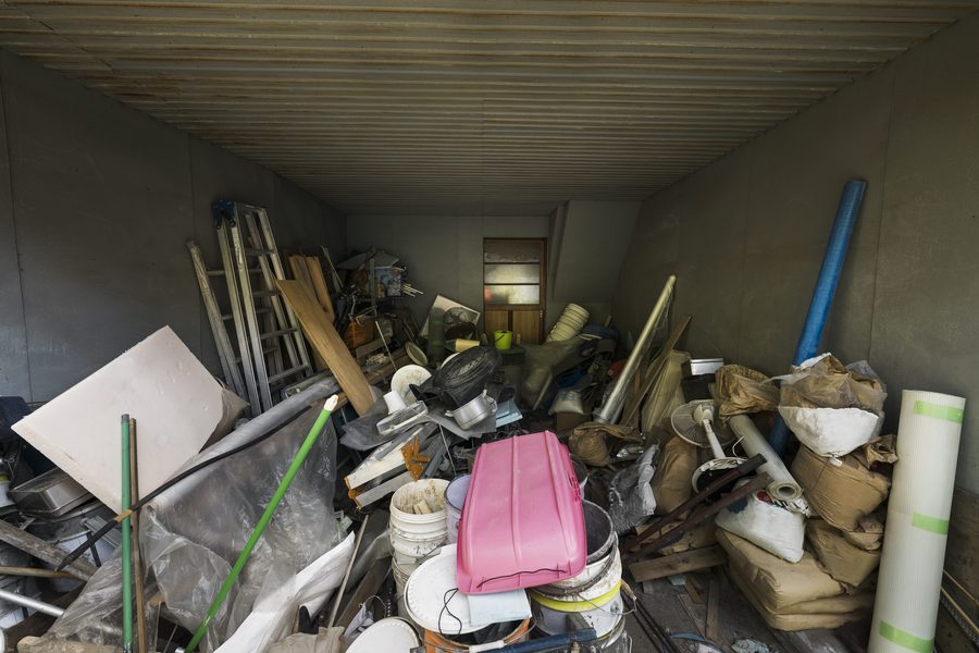 A storage room packed floor to ceiling with household clutter, ladders, buckets and boxes waiting to be cleared
